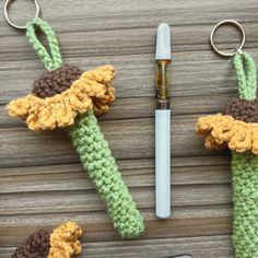 two crocheted items are sitting next to a pen and keychain on a wooden table