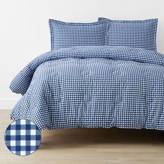 a blue and white checkered comforter set on a wooden floor with a round pillow