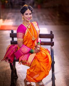 a woman in an orange and pink sari sitting on a bench