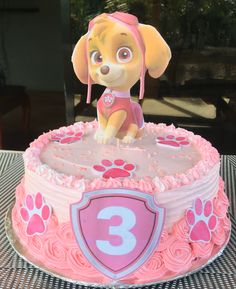 a pink birthday cake with a dog on top