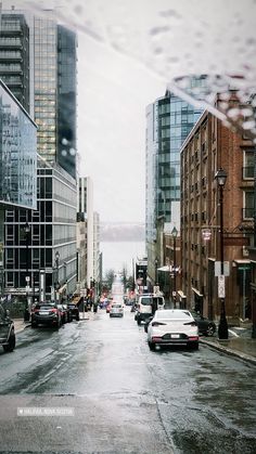 a city street with cars parked on both sides and tall buildings in the back ground