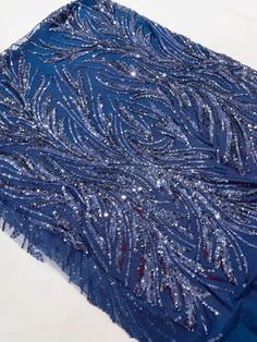 a blue dress with sequins on it is laying on a white tablecloth