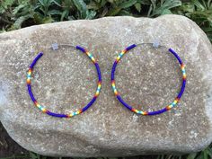 a pair of colorful beaded hoop earrings sitting on top of a rock