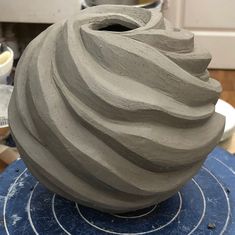 a large gray vase sitting on top of a blue table