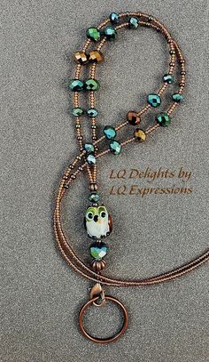 a necklace with an owl on it and two strands of beaded beads hanging from the clasp