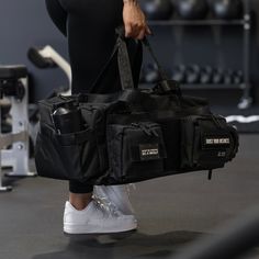 a person holding a gym bag in their hand while standing next to a pair of dumbbells