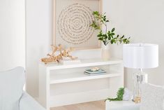 a living room with white furniture and a plant on the side table in front of it