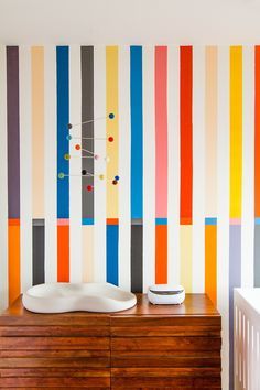 a wooden dresser sitting in front of a wall with colorful stripes painted on the walls