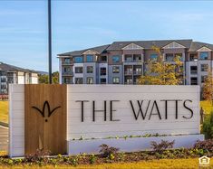 the watts sign in front of an apartment building with trees and grass around it