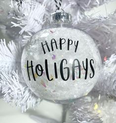 an ornament that says happy holidays on it hanging from a white christmas tree