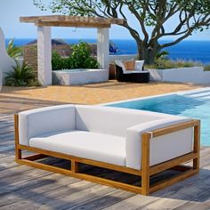 a white couch sitting on top of a wooden floor next to a swimming pool