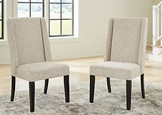 two beige chairs sitting on top of a rug