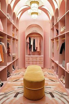 a closet with pink walls and shelves filled with clothes