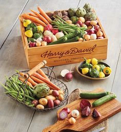 a wooden box filled with assorted vegetables on top of a table next to a cutting board