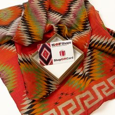 a red scarf with an ornamec design on it and a card in the middle