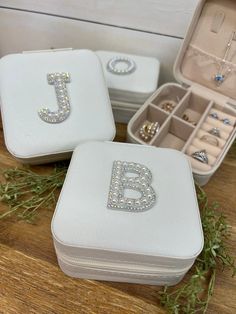 three white jewelry cases sitting on top of a wooden table