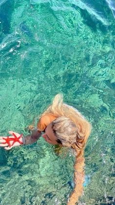 a woman swimming in the ocean with her hands out to catch something on the water