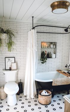 a bathroom with a white brick wall and black bathtub next to a toilet in the corner