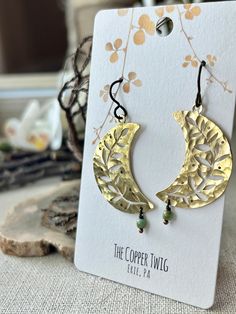 "Hammered raw brass crescent moon with laser cut leaves, accented by tiny green Czech glass beads. Earrings measure 2\" long x 3/4\" wide  Niobium ear wires which are Hypoallergenic - lead & nickel free. (All items in earrings are always lead & nickel free!) These earrings are lightweight and the mixed metal compliments all skin tones! Please feel free to contact me with any questions :)" Handmade Metal Leaf Jewelry, Nickel Free Brass Moon Jewelry, Artisan Crescent Jewelry Nickel Free, Gold Crescent Wire Wrapped Jewelry, Hand Forged Crescent Brass Earrings, Hand Forged Brass Crescent Earrings, Wire Wrapped Crescent Metal Jewelry, Unique Crescent Shaped Copper Jewelry, Nickel-free Half Moon Bohemian Jewelry