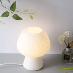 a white lamp sitting on top of a table next to a vase filled with flowers