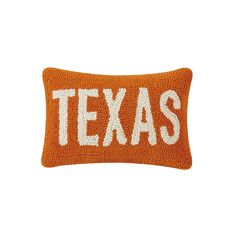 an orange and white pillow with the word texas written in white on it's side