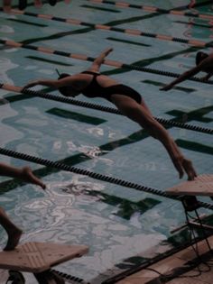 people are swimming in an indoor pool with chairs around them and one person is jumping into the water