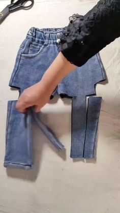 someone is cutting out the bottom part of a pair of jeans