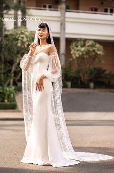 a woman in a white wedding dress standing on the street with her veil over her head