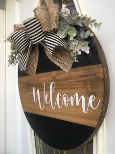 a welcome sign hanging on the side of a door with burlocks and greenery