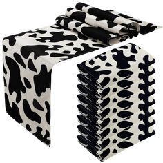 a black and white cow print table cloth with matching napkins on it's sides