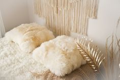 two white pillows sitting on top of a bed next to a wall hanging with fringes