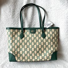 Typically Crafted In The Brand's Monogram Canvas, This Iteration Of Gucci's Famed Ophidia Tote Bag Feels Natural In Its Neutral Straw Construction With The Interlocking G Motif Woven In A Striking Green Hue. Outer: Straw 100%, Leather 100% Product Measurements Depth 5.5 In Handle 10 In Height 11 In Strap 21 In Width 15 In Made In Italy High-end Green Tote Bag, Luxury Green Shoulder Bag For Errands, Luxury Green Bags For Errands, Green Luxury Bag For Errands, High-end Green Shoulder Bag, High-end Green Bags For Shopping, High-end Green Shopping Bag, High-end Green Shoulder Bag With Gold-tone Hardware, Designer Green Shoulder Bag For Travel