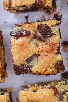 chocolate chip cookie bars are lined up on a sheet of parchment paper, ready to be eaten