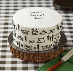 a white cake with black designs on it sitting on a table next to a knife