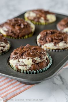 chocolate cupcakes with white frosting in a muffin tin