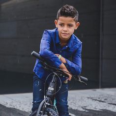 a young boy sitting on top of a bike