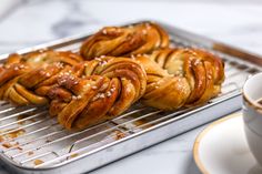 freshly baked croissants sitting on a cooling rack next to a cup of coffee