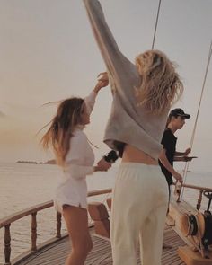 two people are standing on the deck of a boat and one person is holding her hands up