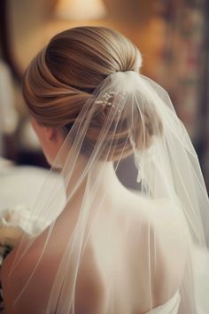 the back of a bride's head with a veil on her wedding day,