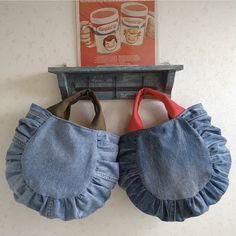 two pairs of blue jean purses hanging on a wall