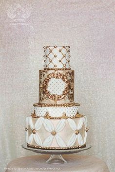 a three tiered wedding cake with white and gold decorations on it's side