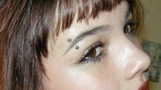 a woman with piercings on her nose looking off to the side