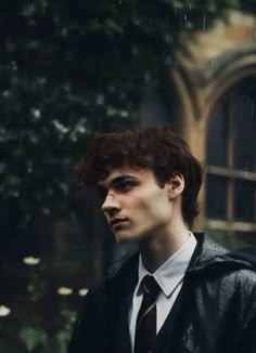 a young man in a suit and tie standing on the street with an umbrella over his head