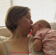 a woman holding a baby and kissing her face with it's mouth wide open