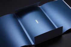 an open blue book with a small logo on the front and back cover, sitting on a black surface