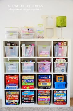 a white bookcase filled with lots of books and plastic containers on top of it