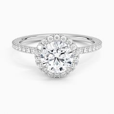 a white gold engagement ring with an oval halo setting and pave set diamonds around the band