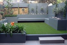 an outdoor garden with artificial grass and plants