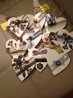 several pieces of paper are arranged in the shape of hearts on a couch cushion, with buttons and ribbons attached to them