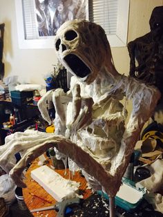 a fake skeleton sitting on top of a table next to a cake covered in icing